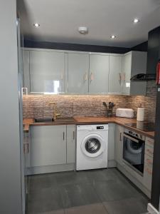 a kitchen with a washing machine and a sink at Beautiful Modern Coventry City Centre Apartment in Coventry