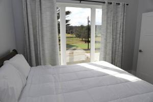 a bedroom with a white bed and a large window at Golf Views Mount Airy in Mount Airy