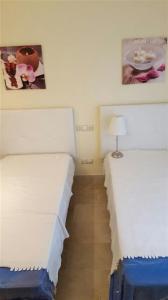Duas camas individuais num quarto com um candeeiro. em Jardines de Nueva Galera em Estepona