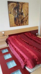 um quarto com uma cama vermelha com uma pintura de um elefante em Jardines de Nueva Galera em Estepona
