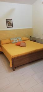 ein Schlafzimmer mit einem großen Bett mit gelber Bettwäsche und Kissen in der Unterkunft Casa Vacanze Villa Giacetta in Santa Maria Del Focallo