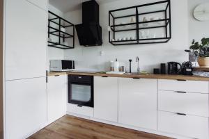 a kitchen with white cabinets and black appliances at Art Apartamenty I Basen & SPA w CENTRUM z balkonem in Lublin