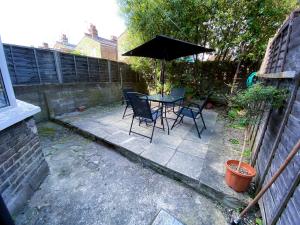 a patio with a table and chairs and an umbrella at 4 BEDROOM HOUSE PARKING & GARDEN NEAR CENTRAL LONDOn in London