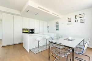 a kitchen with white cabinets and a table and chairs at Villa de Lujo Welcs PDA 073 con Piscina y Vistas al Mar in Platja d'Aro