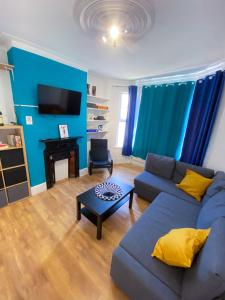 Sala de estar azul con sofá y mesa en 4 BEDROOM HOUSE PARKING & GARDEN NEAR CENTRAL LONDOn, en Londres