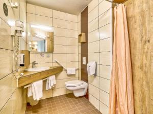 a bathroom with a toilet and a sink and a mirror at B&B HOTEL Clermont-Ferrand Sud Aubière in Aubière