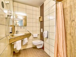 La salle de bains est pourvue de toilettes, d'un lavabo et d'un miroir. dans l'établissement B&B HOTEL Clermont-Ferrand Sud Aubière, à Aubière