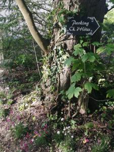 a sign on the side of a tree with flowers at Chambre E André Le Domaine Des Jardins De Bracquetuit in Bracquetuit