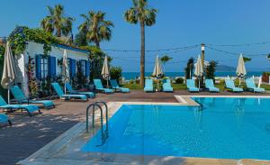 Uras Beach Hotel في فتحية: مسبح وكراسي ومظلات بجانب مبنى