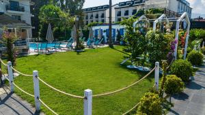 Uras Beach Hotel في فتحية: حديقة بها سور الحبل وحمام سباحة