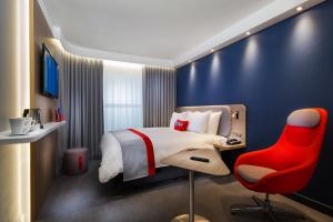 une chambre d'hôtel avec un lit et un fauteuil rouge dans l'établissement Holiday Inn Express Oberhausen, an IHG Hotel, à Oberhausen