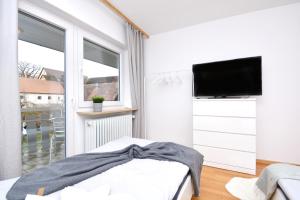 ein weißes Schlafzimmer mit einem Flachbild-TV und einem Bett in der Unterkunft ROH02-RI Apartment in Rohr 