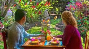 Um homem e uma mulher sentados à mesa com comida. em Boquete Garden Inn em Boquete