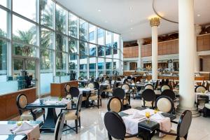 un restaurante con mesas, sillas y ventanas en Sheraton Jumeirah Beach Resort, en Dubái