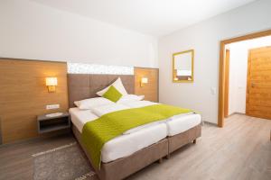 a bedroom with a large bed with a green blanket at Hotel-Café-Restaurant Matzelsdorfer Hof in Millstatt