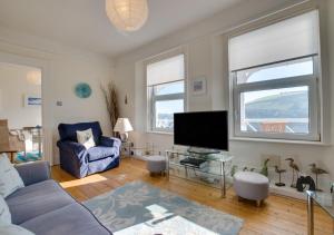uma sala de estar com um sofá e uma televisão em 4 Thurlestone Court em Dartmouth