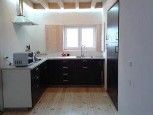 a kitchen with black cabinets and a sink and a window at Taipa 2 - Casas de Campo do Junqueirinho in Bicos