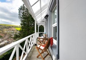 uma varanda com uma mesa e cadeiras numa casa branca em 4 Thurlestone Court em Dartmouth