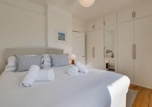 um quarto branco com uma grande cama branca com almofadas em 4 Thurlestone Court em Dartmouth