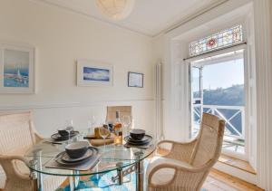 uma sala de jantar com uma mesa de vidro e cadeiras em 4 Thurlestone Court em Dartmouth