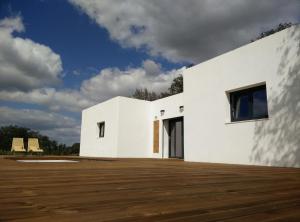 a white house with a wooden floor at Taipa 2 - Casas de Campo do Junqueirinho in Bicos