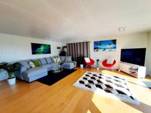 - un salon avec un canapé bleu et des fauteuils rouges dans l'établissement Cosy family home with pool, à Grimstad