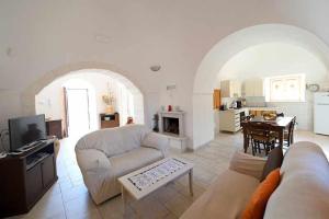 a living room with a couch and a table and a kitchen at Trullo Antico with exclusive swimming pool in Cisternino