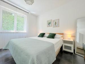 een witte slaapkamer met een bed en een spiegel bij Rab City Apartment Greeny in Rab