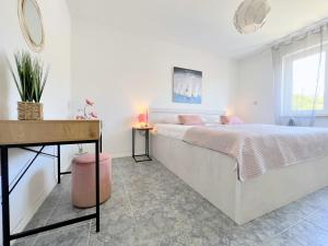 a white bedroom with a large bed and a desk at Rab City Apartment Greeny in Rab