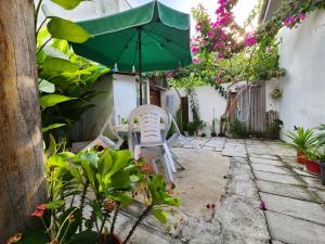 un patio con sombrilla verde, sillas y plantas en Jerrys Dive Lodge Rasdhoo en Rasdu