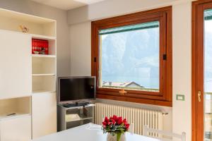 a room with a table with a television and a window at Casa Aria in Riva di Solto