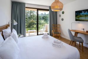 a bedroom with a white bed with a desk and a window at Domaine Les Sources de Dieulefit in Dieulefit