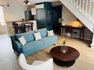 ein Wohnzimmer mit einem blauen Sofa und einem Tisch in der Unterkunft Hotel Le Cardinal Rueil Centre in Rueil-Malmaison