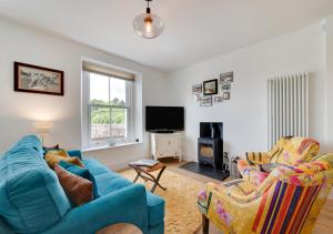 Sala de estar con 2 sillas azules y TV en Oystershell Cottage en Kingswear