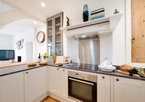 uma cozinha com armários brancos e um forno com placa de fogão em Oystershell Cottage em Kingswear