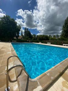 een groot blauw zwembad met een stoel ernaast bij Cabourg - Appartement - 4 pers - 1 ch - Piscine in Cabourg