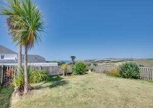 a yard with a fence and a palm tree at Island View in Thurlestone