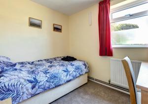 a bedroom with a bed with a blue and white blanket at Bidwell Brook in Paignton