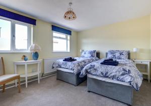 a bedroom with two beds and a chair and windows at Bidwell Brook in Paignton