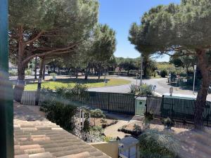 a view of a park with trees and a fence at La Bergerie in Cap d'Agde