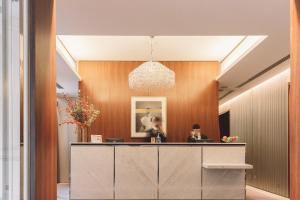 a lobby with a reception desk with two people at Hôtel De Sers Champs Elysées Paris in Paris