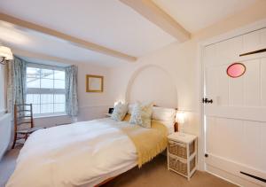 a bedroom with a large white bed and a window at Jasmine Cottage in Brixham