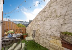 a patio with a table and chairs next to a wall at Jasmine Cottage in Brixham