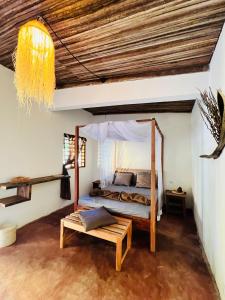 a bedroom with a canopy bed and a bench at NatShi Lodge in Ambaro
