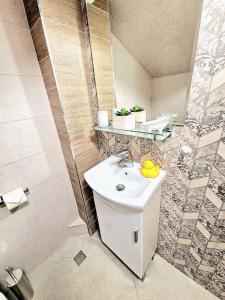 a bathroom with a white sink and a shower at Art Apartment + 2BD parking space in Varna City