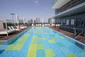 a large swimming pool with blue and green tiles on the side of a building at Midtown Tel Aviv Luxury Apartment in Tel Aviv