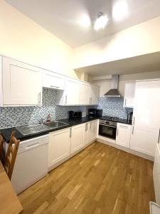 a kitchen with white cabinets and a wooden floor at Camden Budget Suites - Next to Station and Camden Market in London