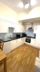 a kitchen with white cabinets and a wooden floor at Camden Budget Suites - Next to Station and Camden Market in London