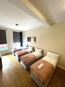 a hotel room with three beds and a couch at Camden Budget Suites - Next to Station and Camden Market in London