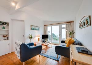 a living room with two blue chairs and a television at Gulls Cry in Stoke Fleming